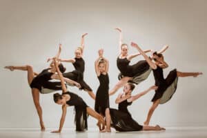 A group of dancers in black outfits doing different poses.