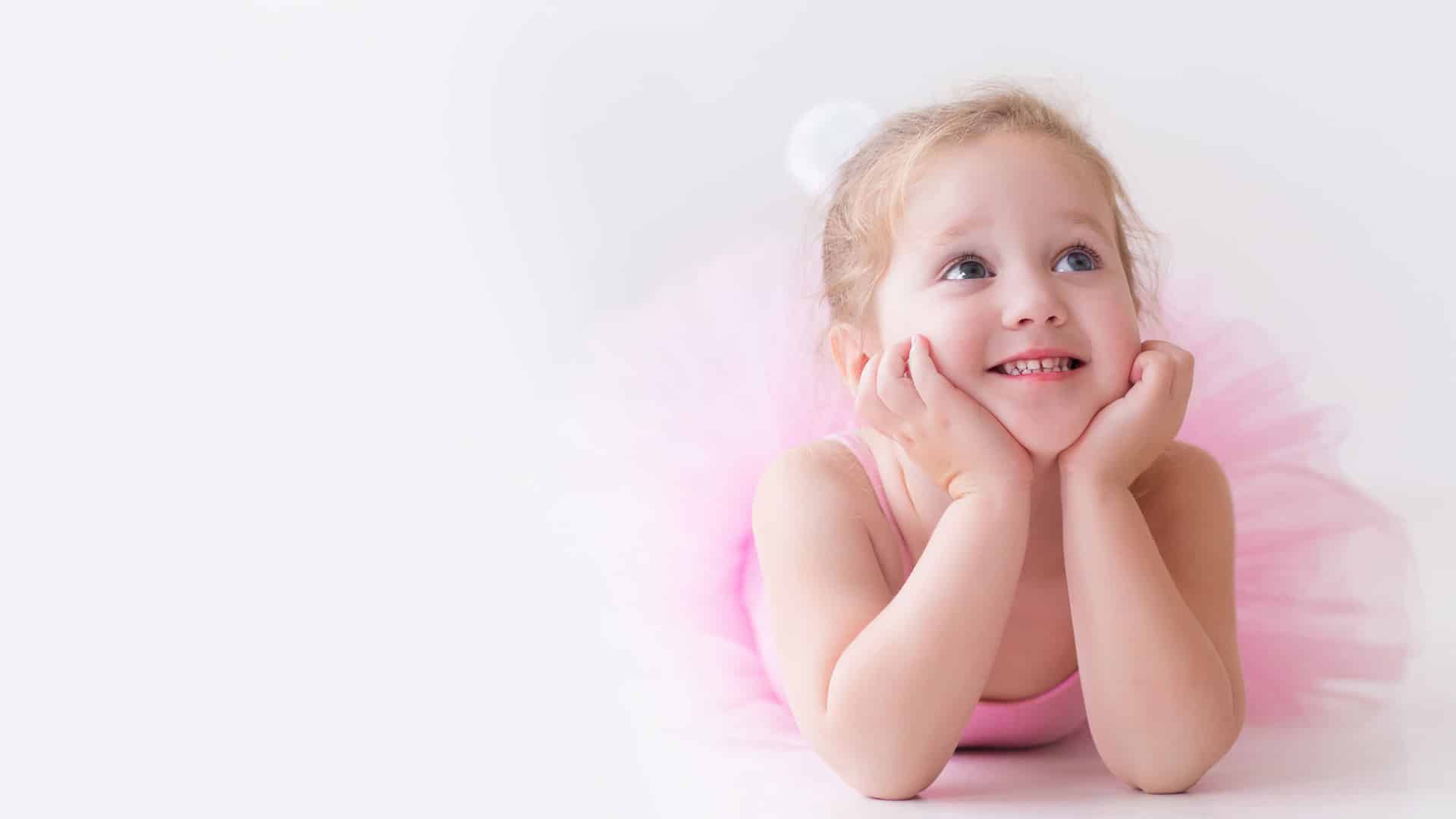 Smiling ballerina in pink tutu, looking up.