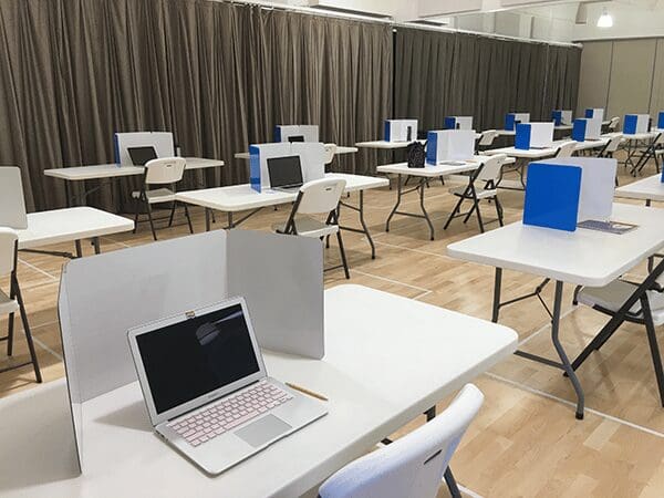 Laptop on desk with divider in classroom.