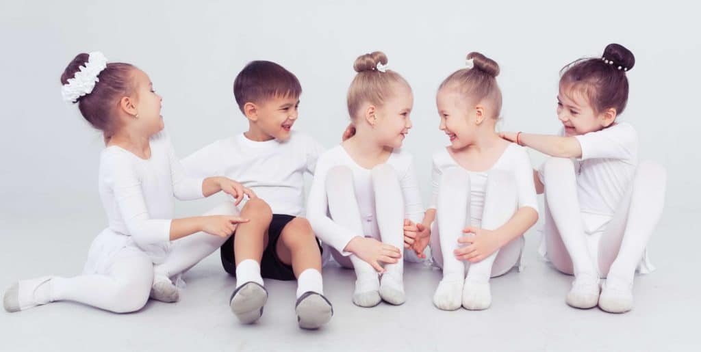 Four children in white clothes smiling.