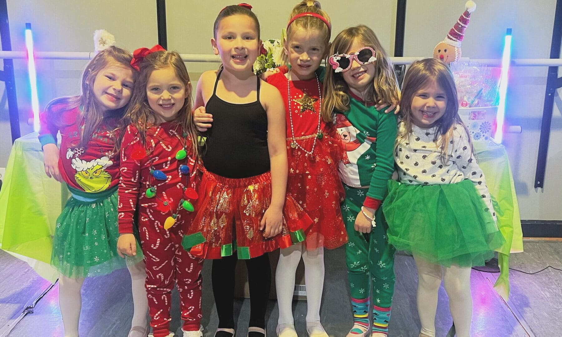 Girls in festive Christmas outfits smiling.